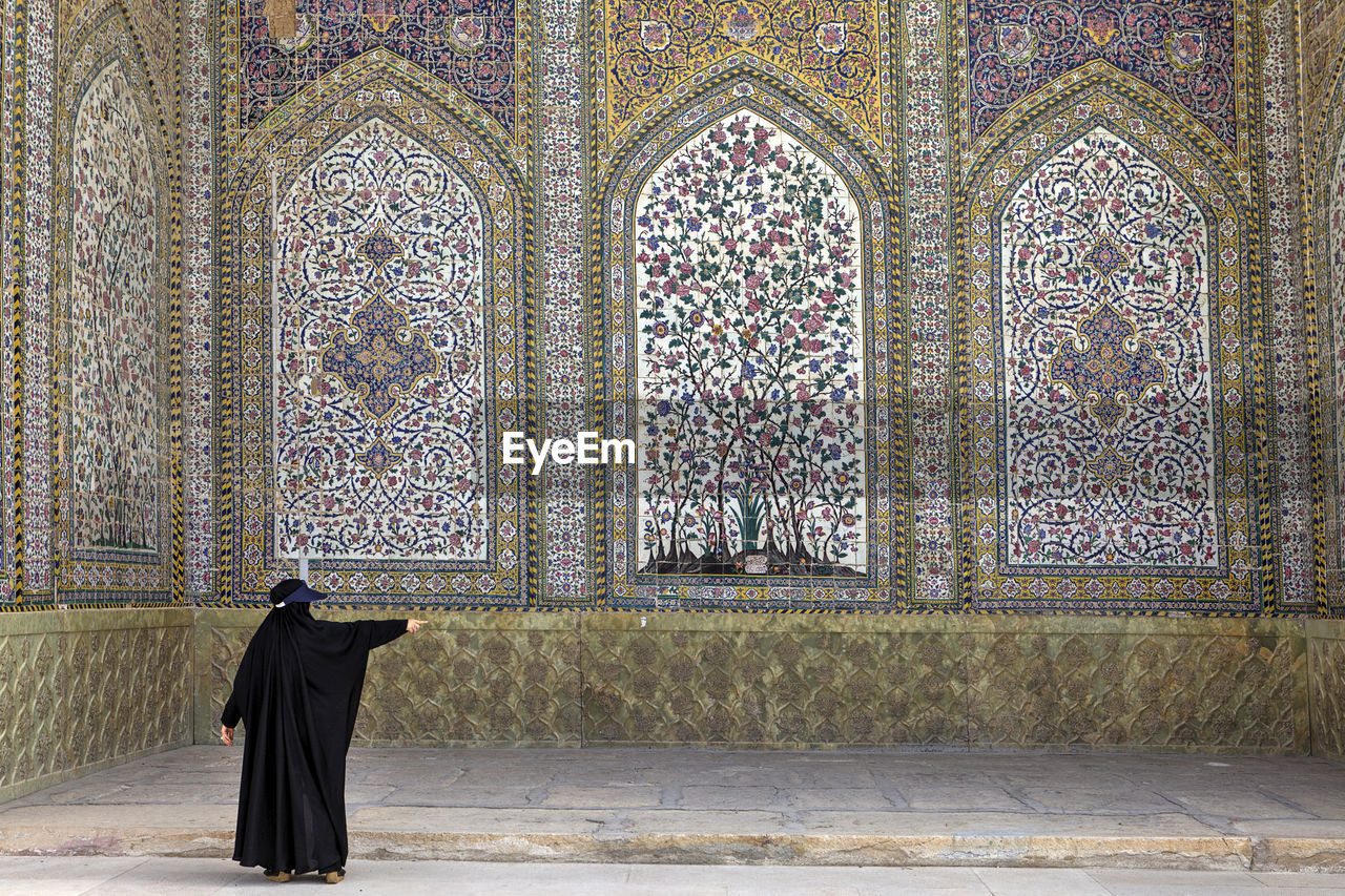 Rear view of woman standing against wall in mosque