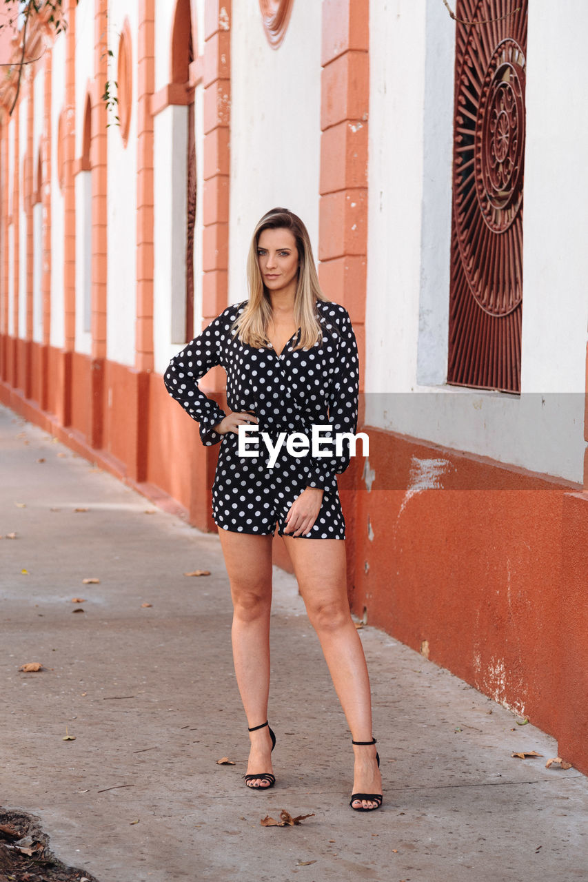 Full length portrait of woman standing on footpath