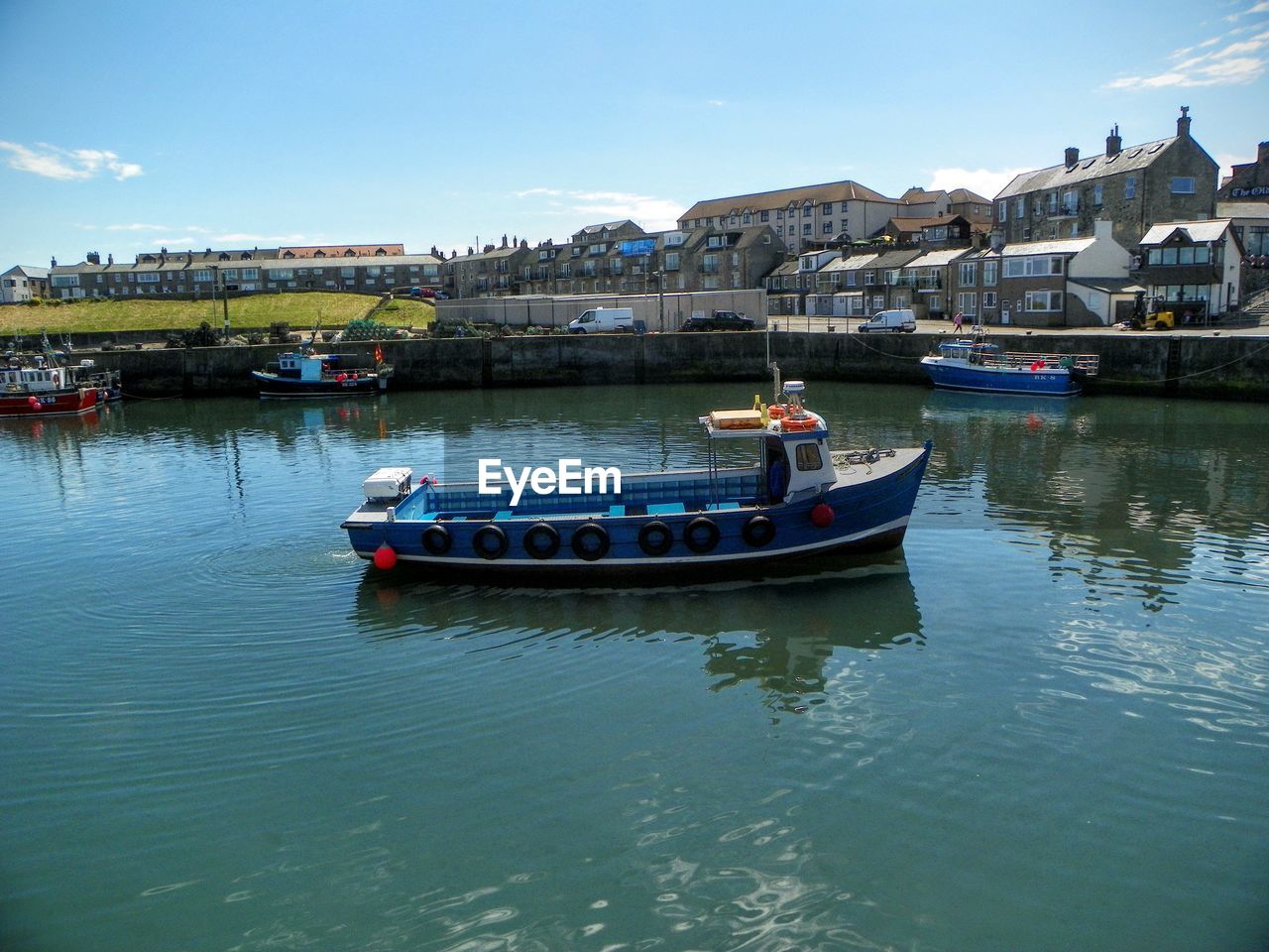 Boats moored at river by street and buildings against sky