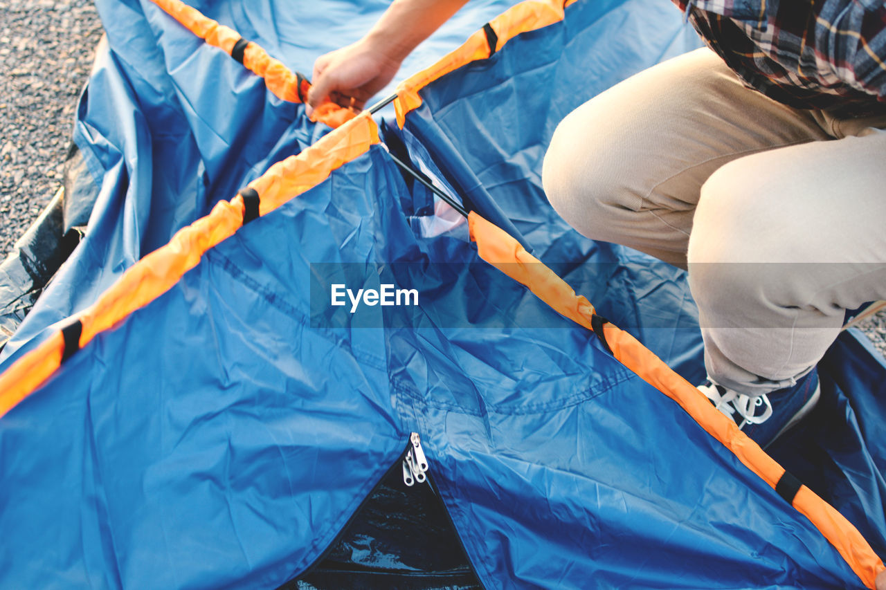 Low section of man crouching on blue tent
