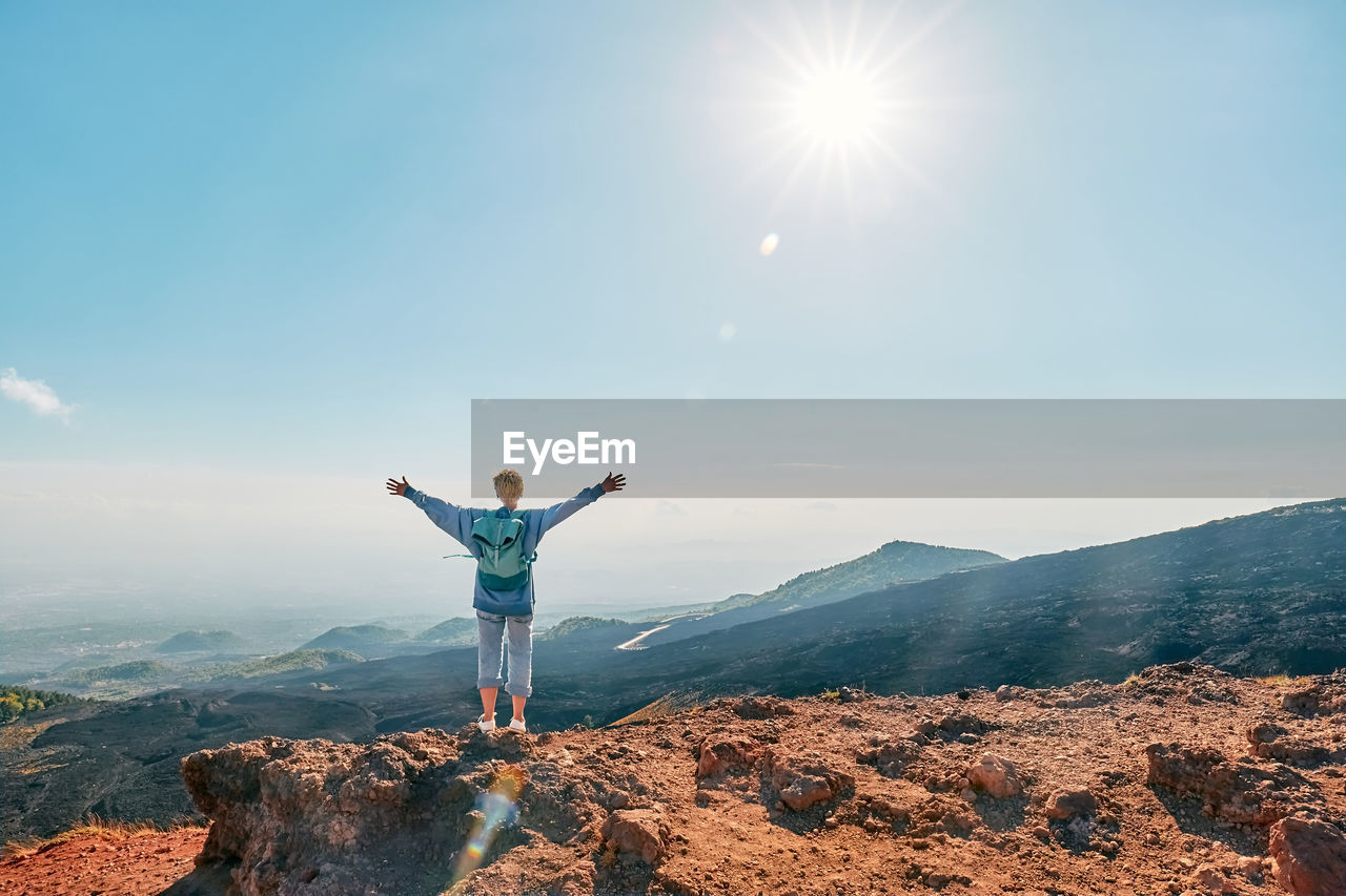 Tourist woman enjoying freedom with open hands, while admiring panoramic view of volcano etna.