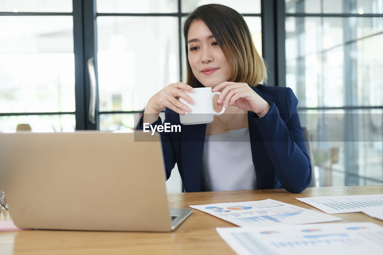 MID ADULT WOMAN DRINKING COFFEE CUP