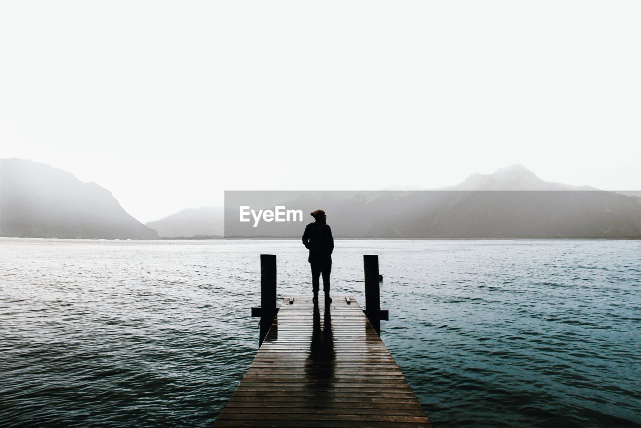 Man standing on lake against clear sky