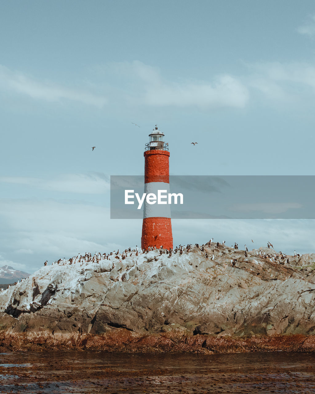 Lighthouse by sea against sky