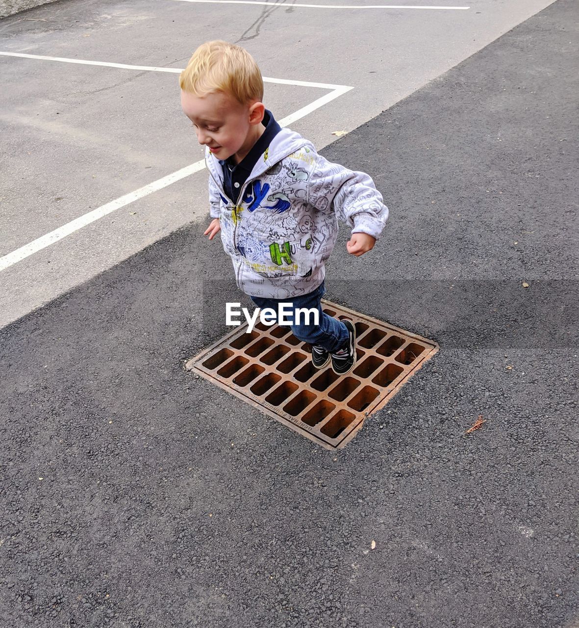 HIGH ANGLE VIEW OF CUTE BOY SKATEBOARDING ON ROAD