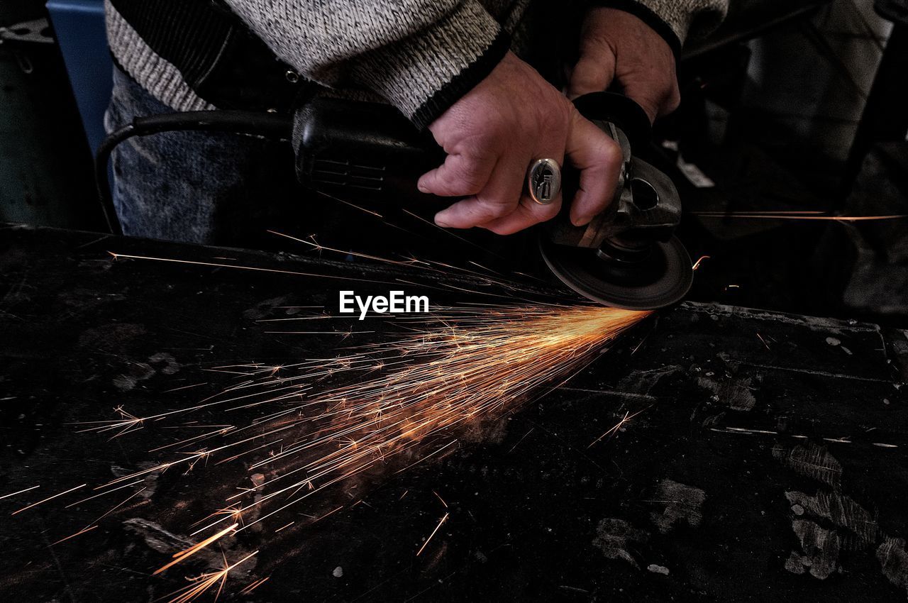 Midsection of man using circular saw at industry