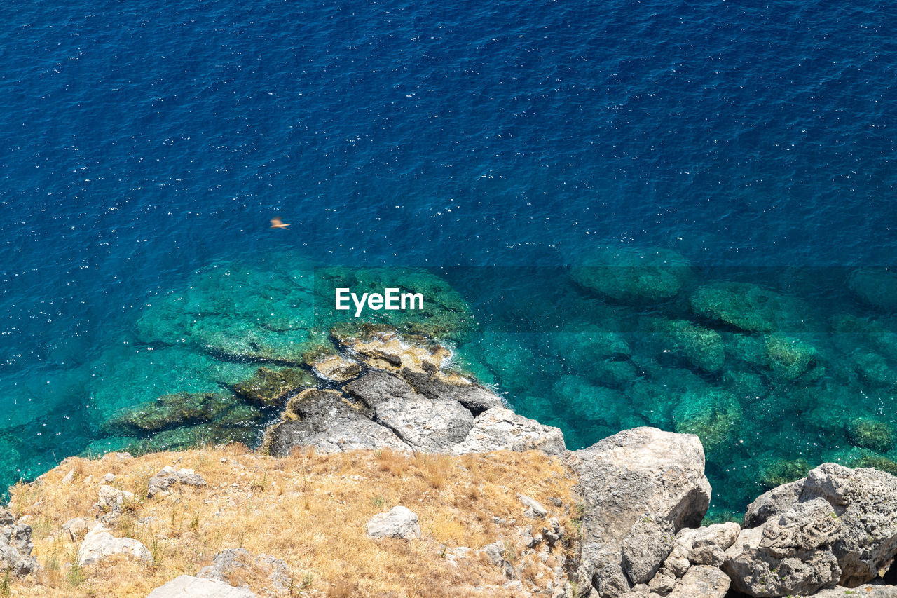 View from the acropolis on the rocky coast with blue and turquoise water in lindos on rhodes island