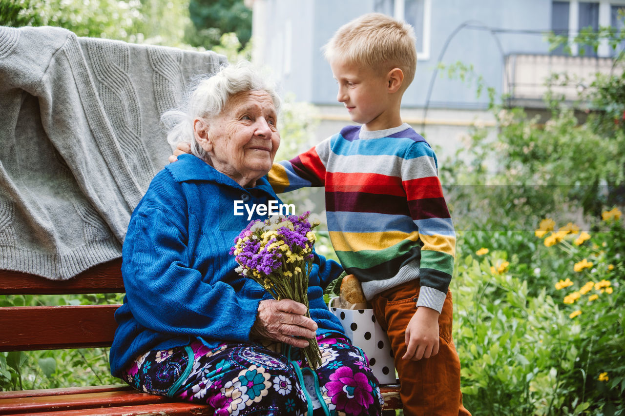 Grandparents day, reunited family, togetherness. senior old grandma hugs grandson outdoors