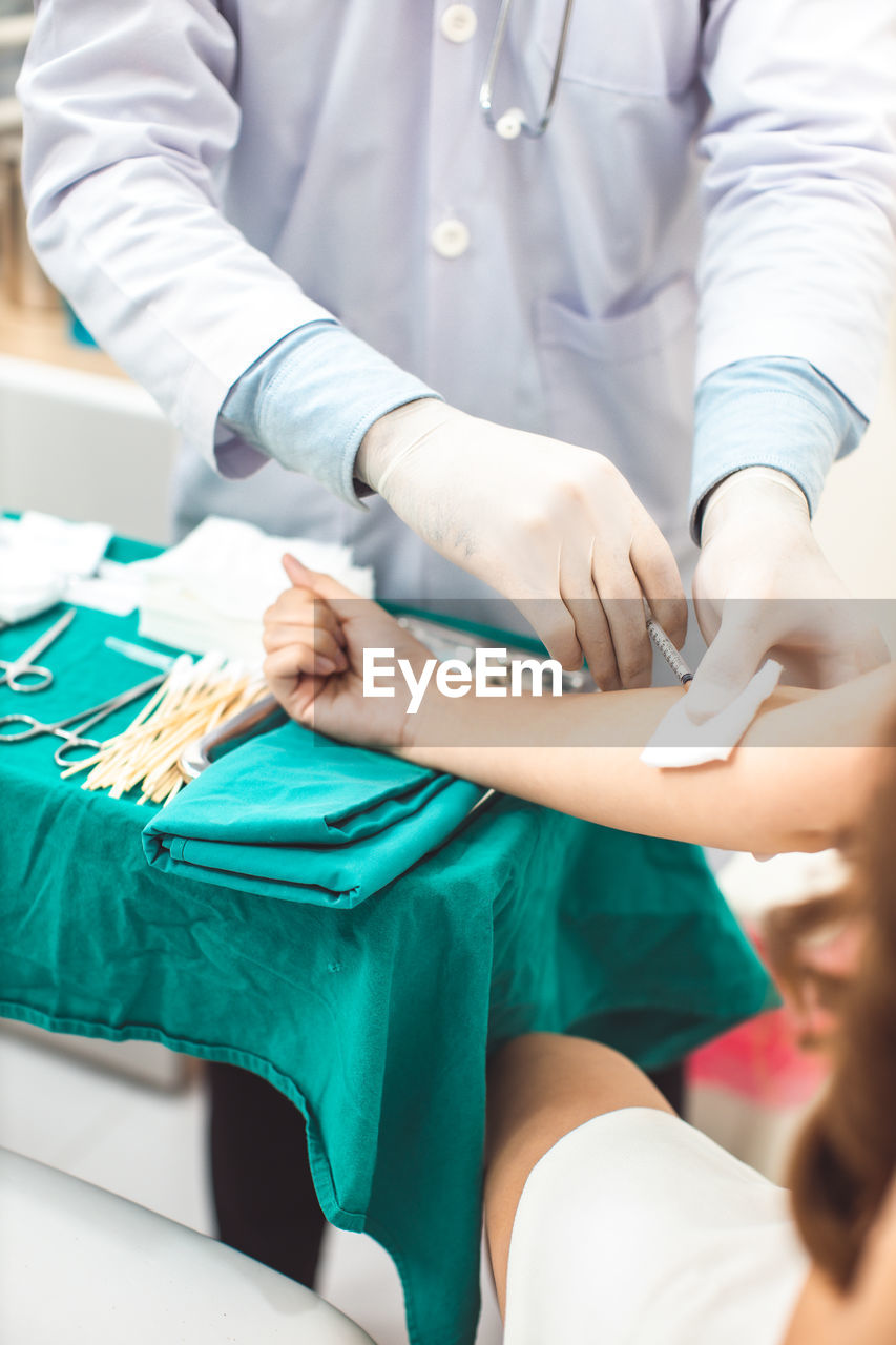 Midsection of doctor vaccinating woman