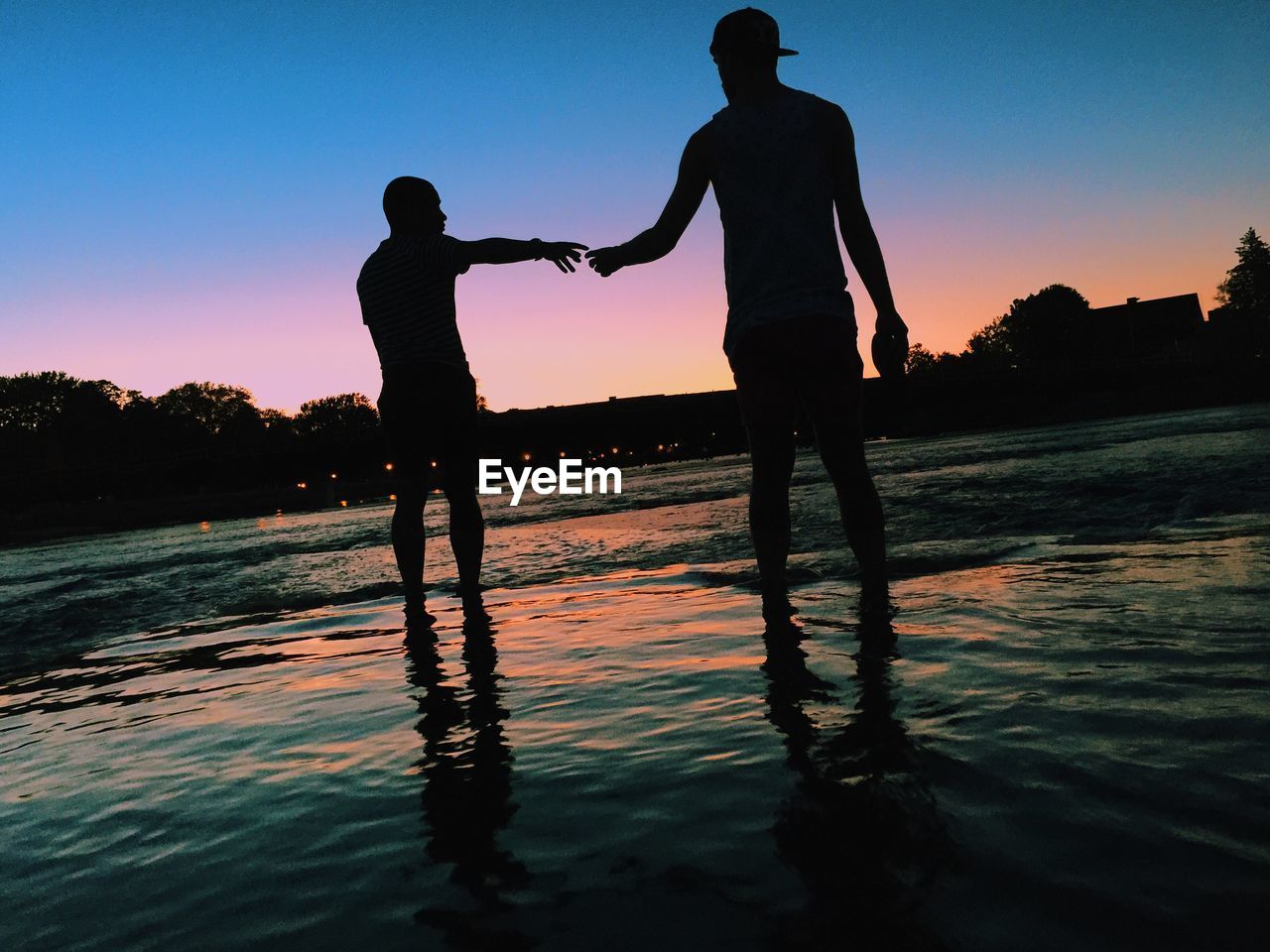 SILHOUETTE MEN STANDING ON WATER AGAINST SKY