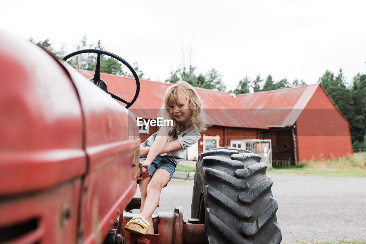 Girl sat on a tractor smiling whilst at a farm in sweden