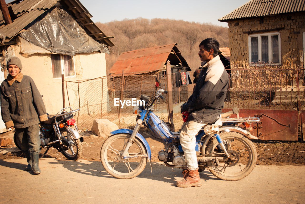 MEN RIDING BICYCLE ON STREET AGAINST BUILDINGS