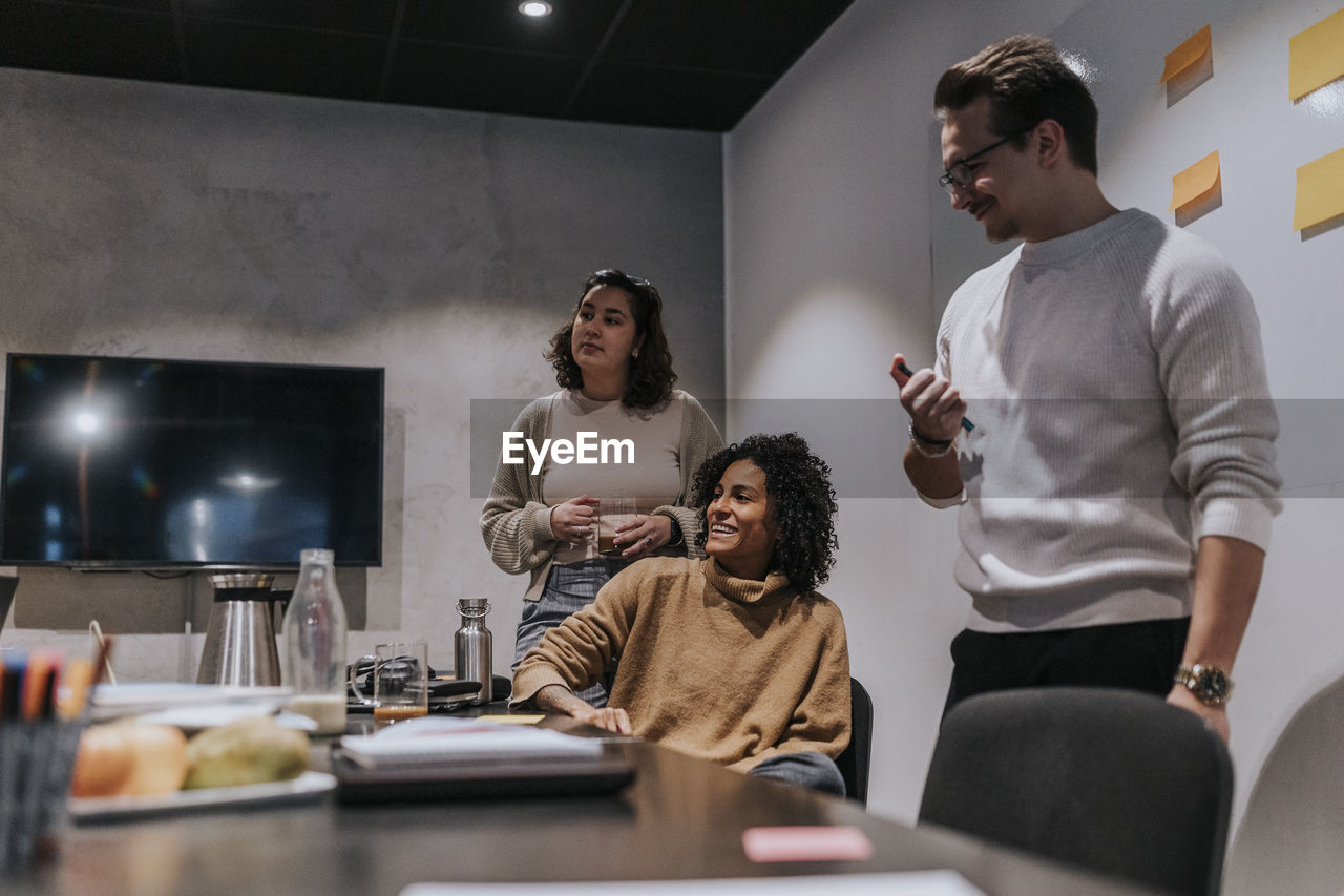 Smiling multiracial male and female colleagues discussing strategy in board room at office