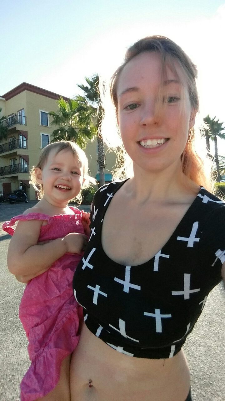 Portrait of smiling mother and daughter on road in city