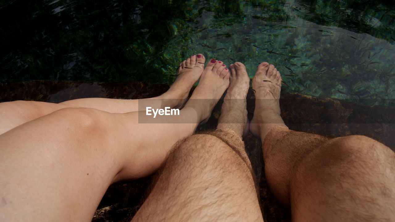 Low section of couple relaxing in swimming pool