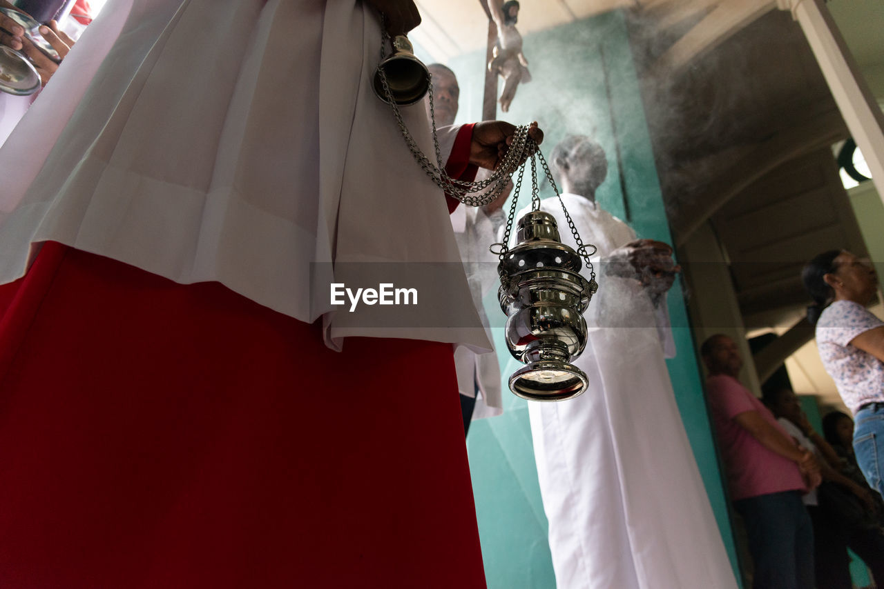 Lower part of catholic church members with incense in the campo santo 