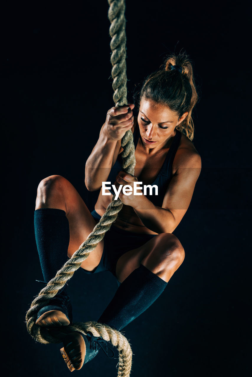 High angle view of woman climbing rope at gym 