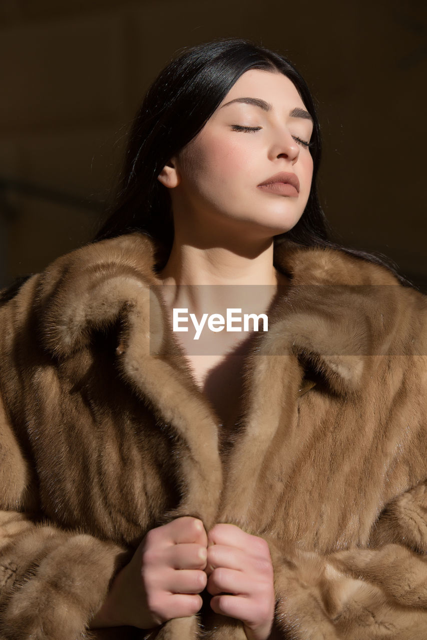 CLOSE-UP OF A YOUNG WOMAN WITH HAND IN WINTER