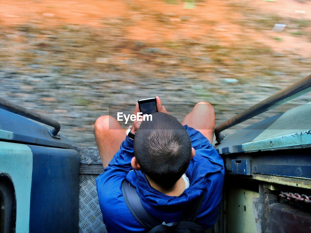 Directly above shot of boy using mobile phone at entrance of train