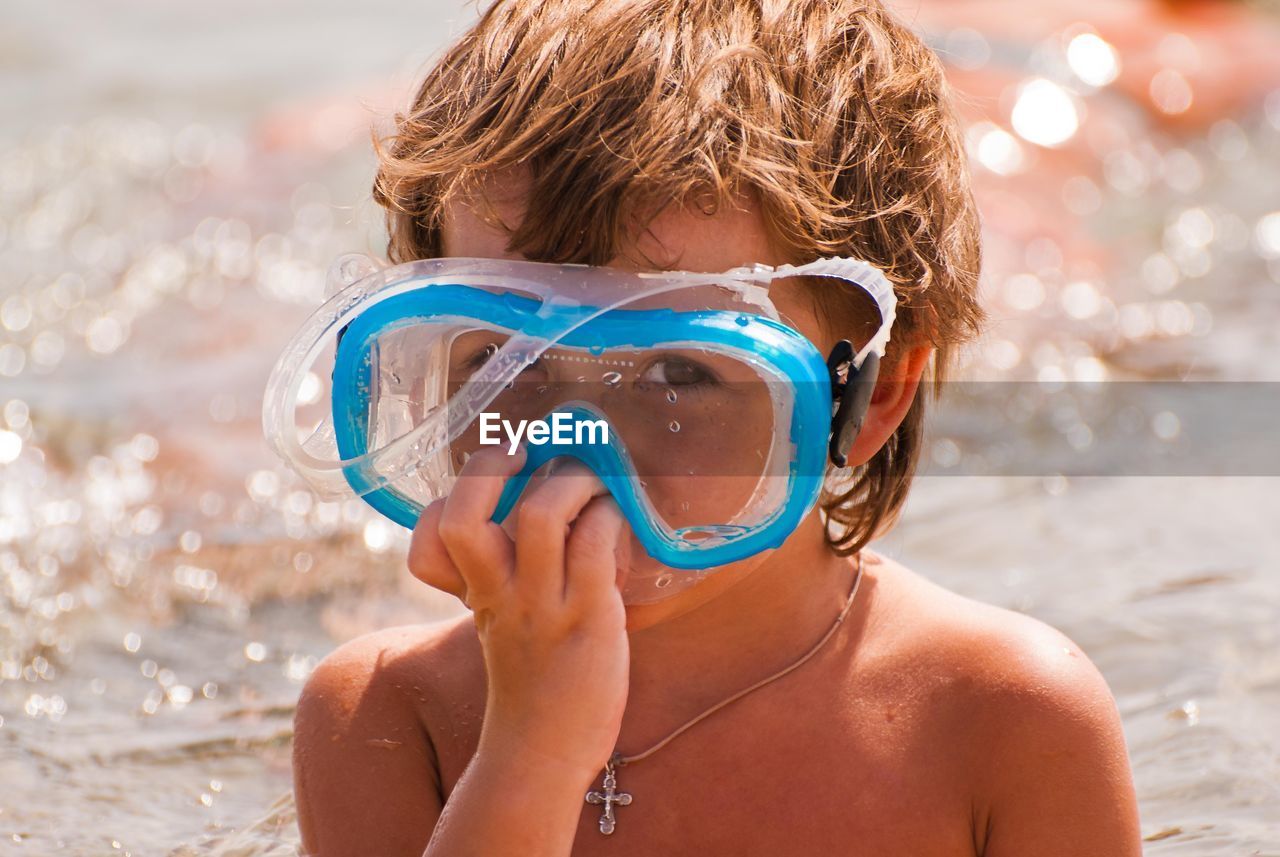 Cute boy looking through the glass of a diving mask