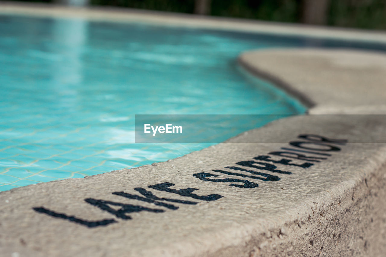 CLOSE-UP OF TEXT ON SWIMMING POOL AT SHORE