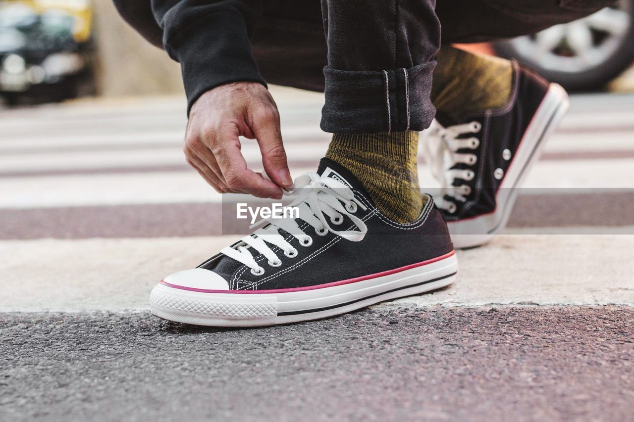 Low section of man tying shoelace on road