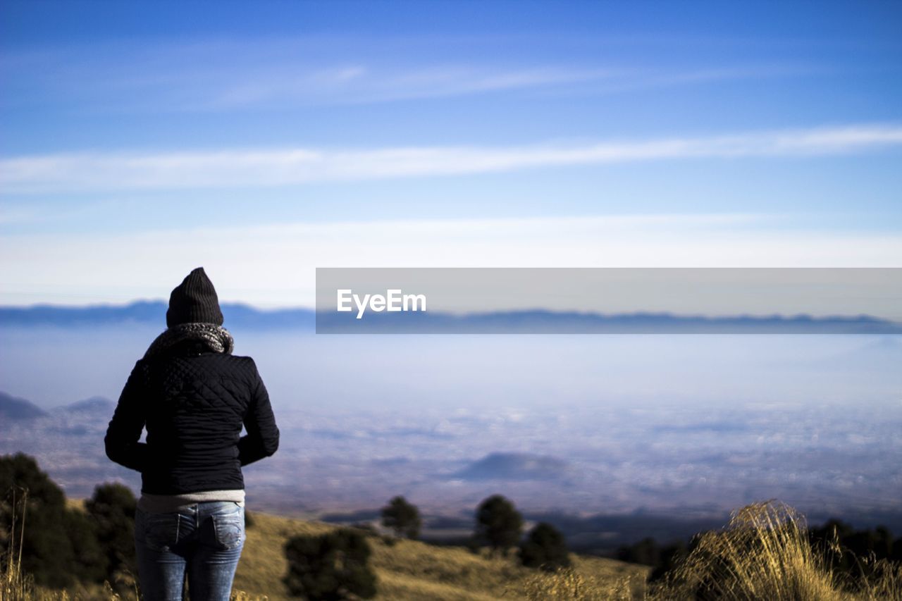 Rear view of woman standing against foggy landscape