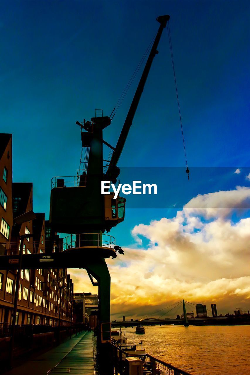 CRANES AT CONSTRUCTION SITE AGAINST SKY