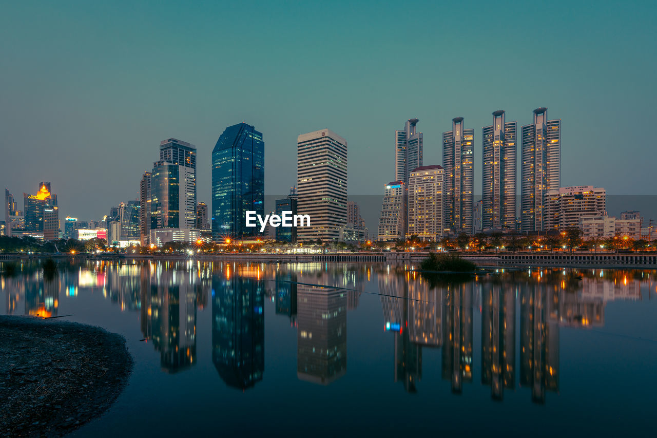 Reflection of illuminated buildings in river against sky