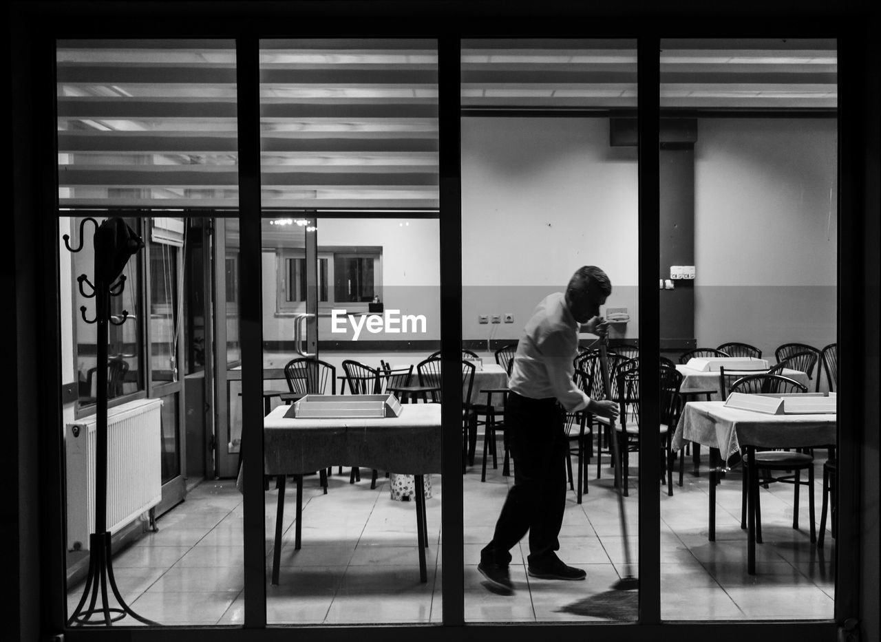 FULL LENGTH OF WOMAN STANDING IN CORRIDOR OF BUILDING