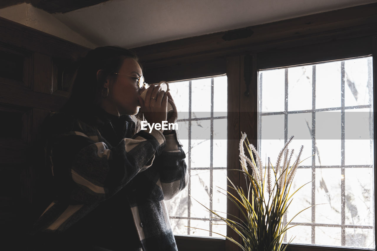 YOUNG WOMAN LOOKING AT WINDOW