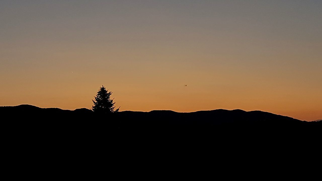 SILHOUETTE LANDSCAPE AGAINST CLEAR SKY DURING SUNSET