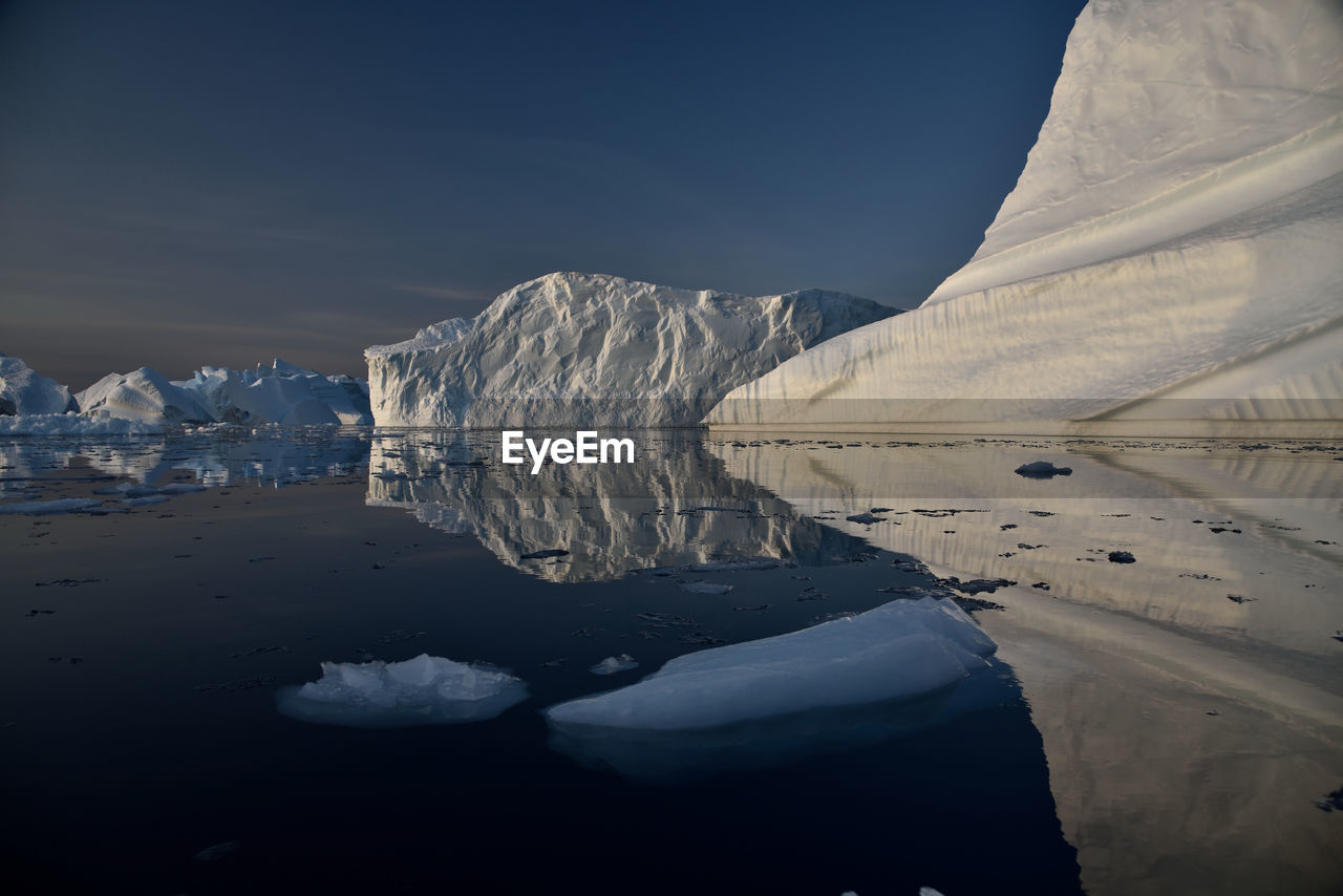 Scenic view of iceberg shapes and reflectins in mirror-like sea in greenland scoresby sound