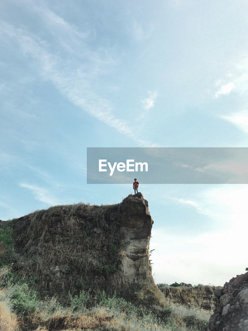 Low angle view of man on rock against sky