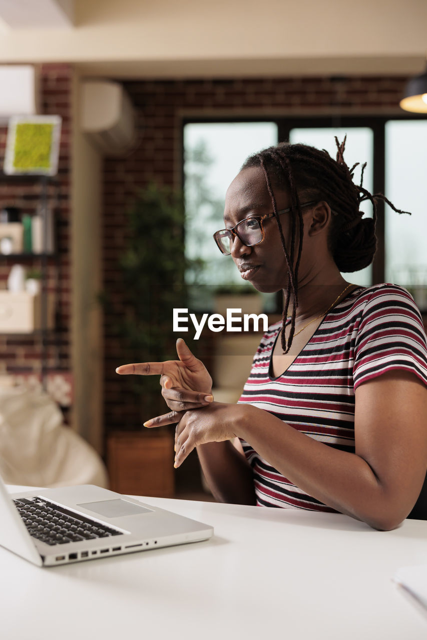 side view of woman using laptop at home