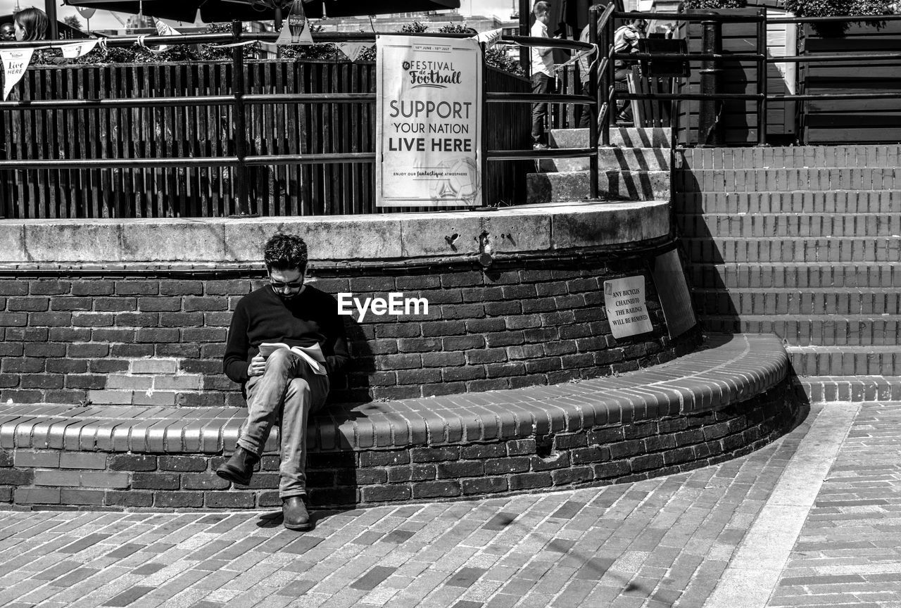 FULL LENGTH OF MAN SKATEBOARDING ON COBBLESTONE STREET