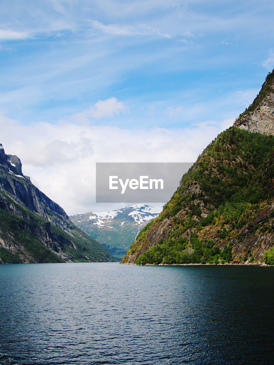Scenic view of fjord by mountains against sky