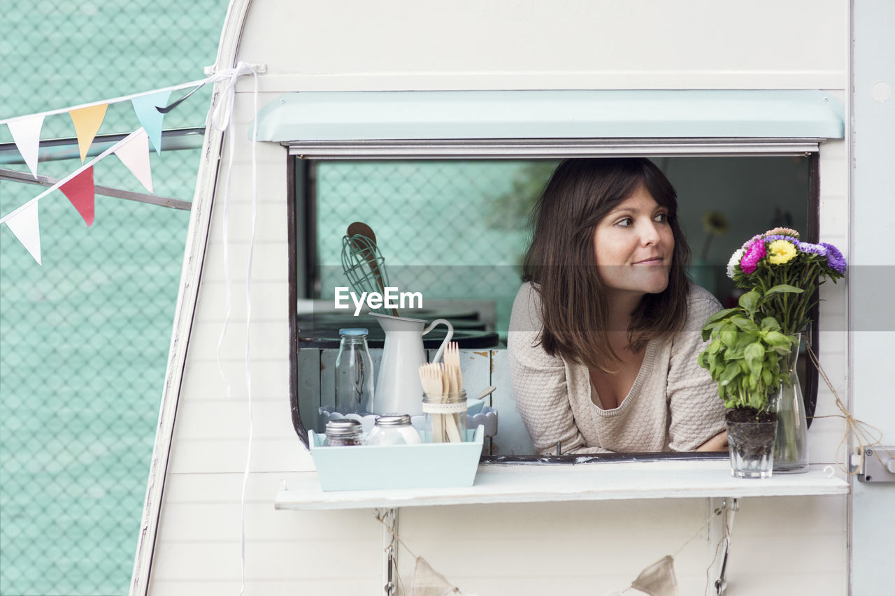 Thoughtful female owner looking out through food truck window