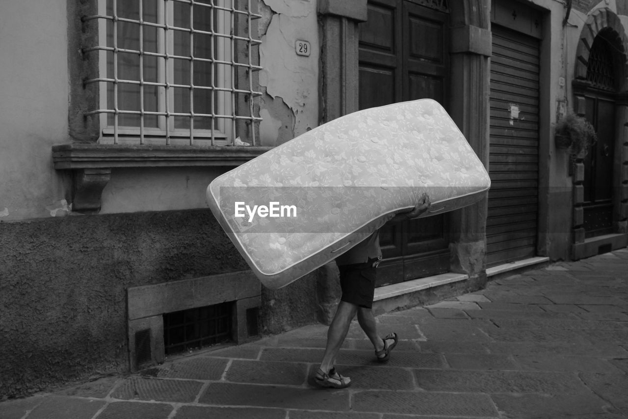 Man carrying mattress on street