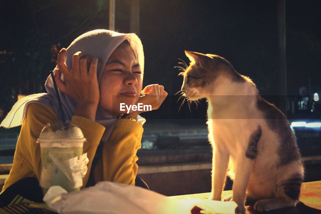 Woman in hijab looking at cat 