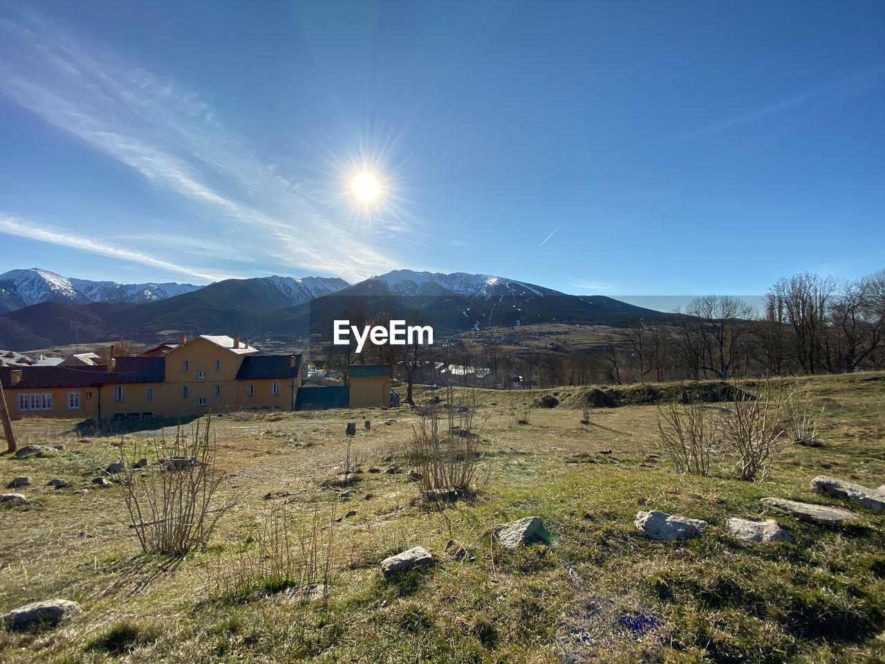 SCENIC VIEW OF FIELD BY MOUNTAINS AGAINST BRIGHT SUN