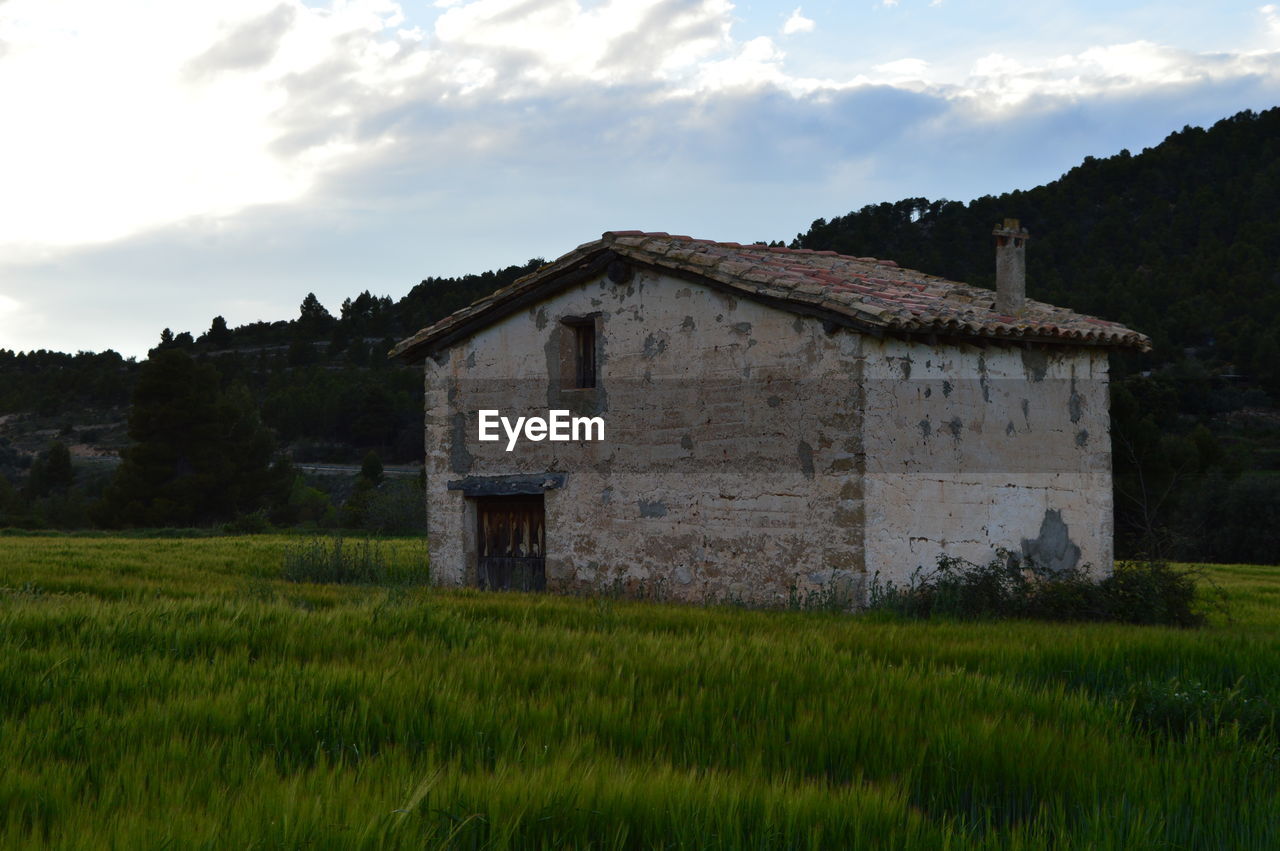 BUILT STRUCTURE ON GRASSY FIELD AGAINST SKY