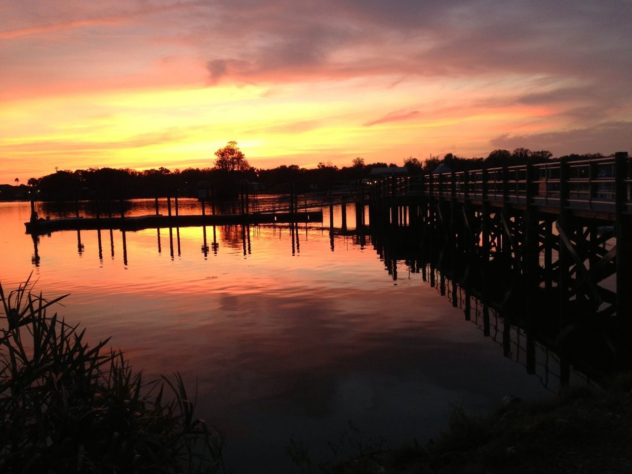 Pier over calm lake during sunset