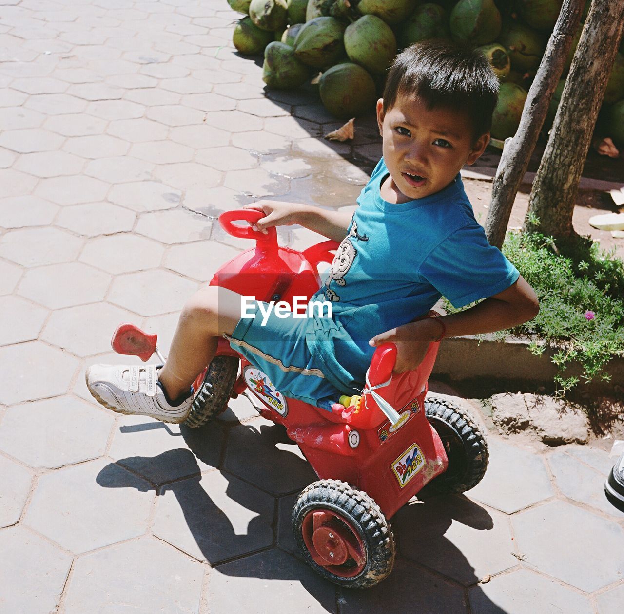 FULL LENGTH PORTRAIT OF BOY SITTING ON STONE