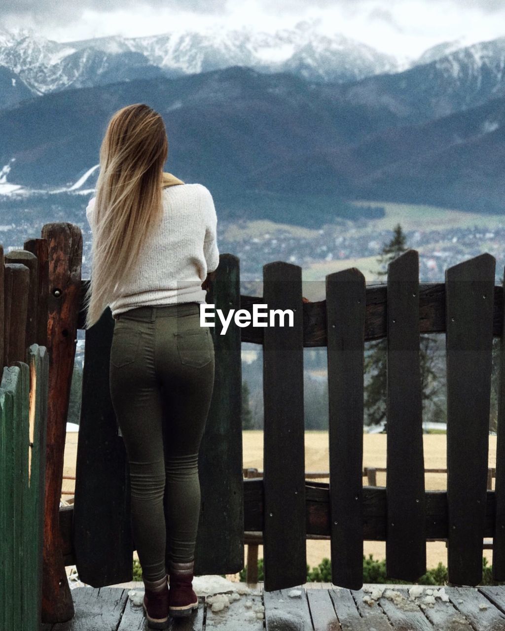 Rear view of woman standing by railing against mountains