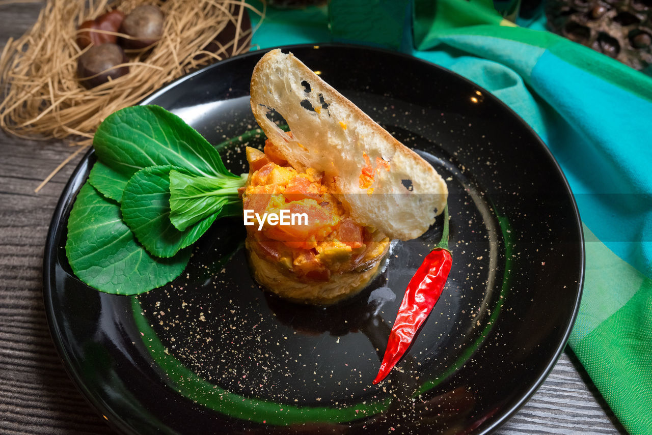 Chicken escalope with spicy tomato and olive relish. slim slice of crouton, chili pepper, pak choi