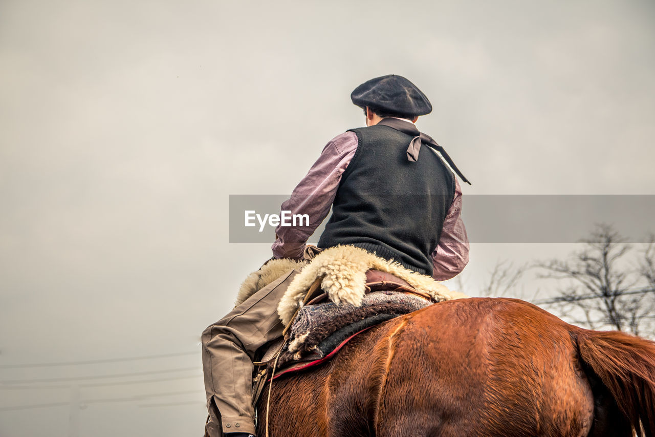 Midsection of man riding horse against sky