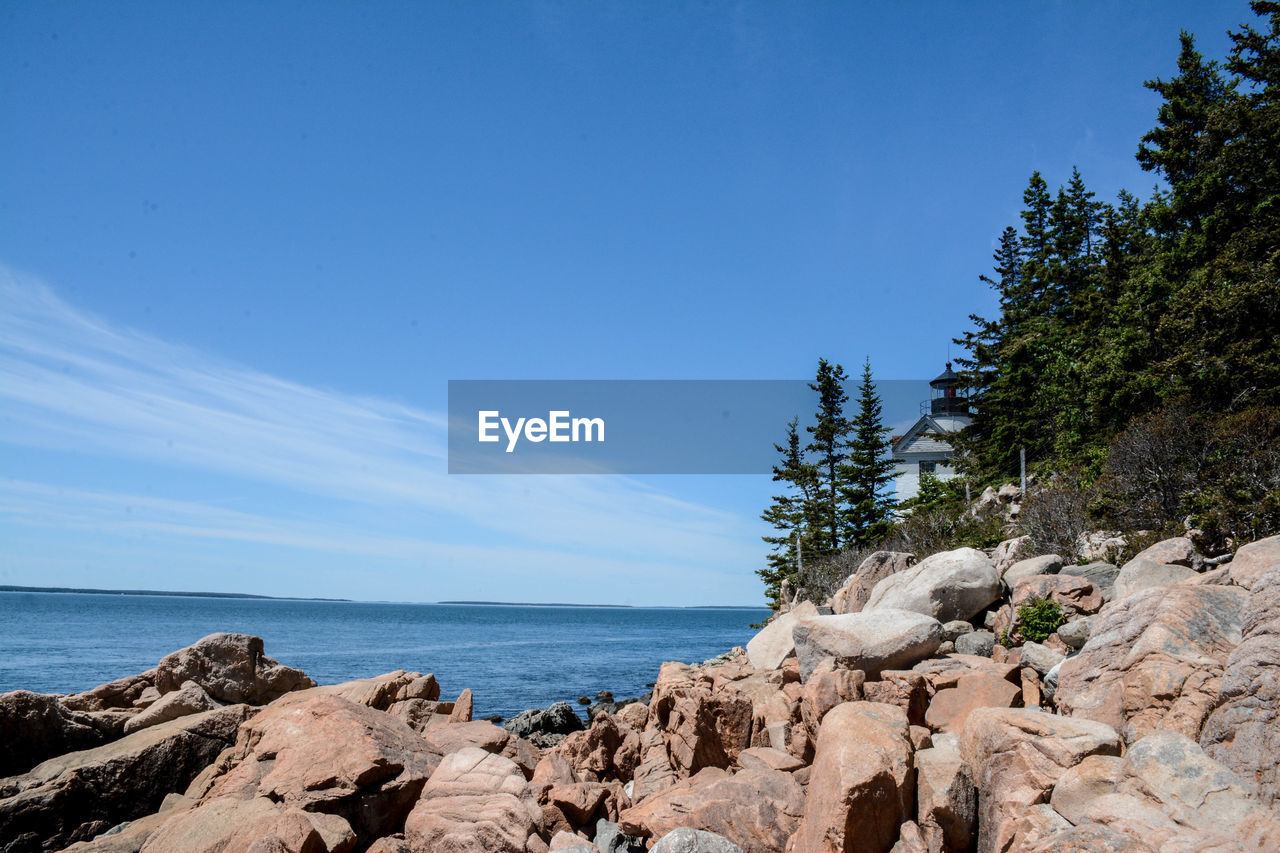 Rocks by sea against blue sky