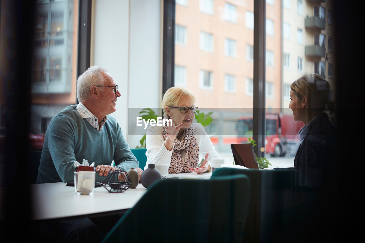 Senior woman with man talking to real estate agent in office