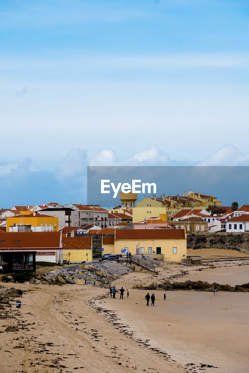 Beach by buildings against sky